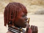 Jihozpadn Etiopie, dol Omo, Turmi: Dvka z kmene Hamar na slavnosti skkn pes bky. Stejn jako ostatn dvky na slavnosti m vlasy m naputn sms erven hlinky a tuku.